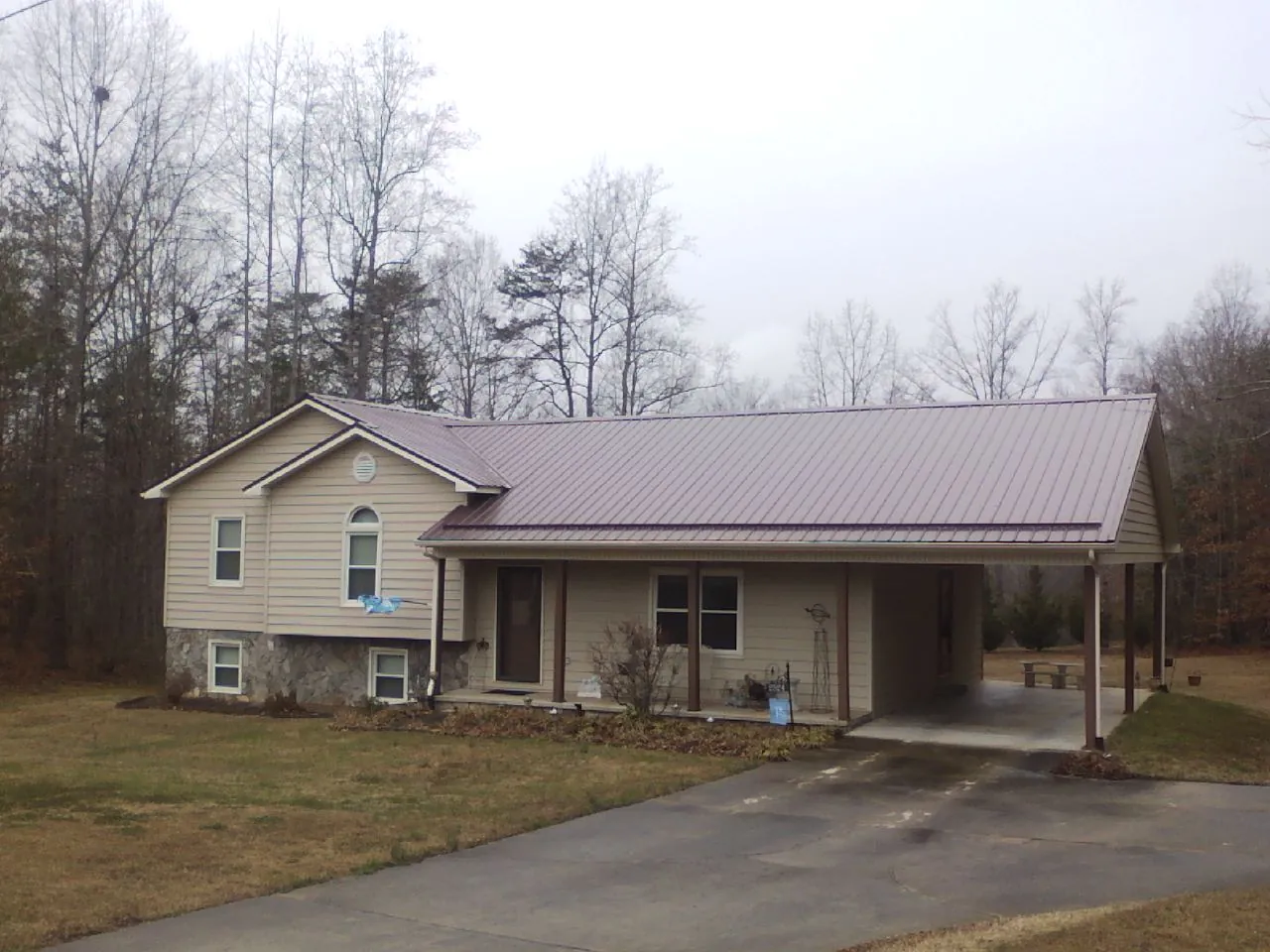 Burgundy metal roof on a tan split level home with an attached carport in Skaneateles Falls