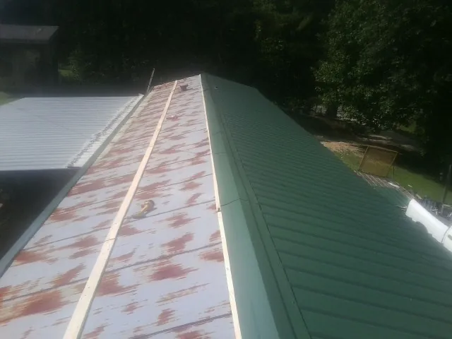 Old rusted panels beside newly installed green metal roofing — Wind Damage Roof Repair by Roofing Brothers in Skaneateles Falls