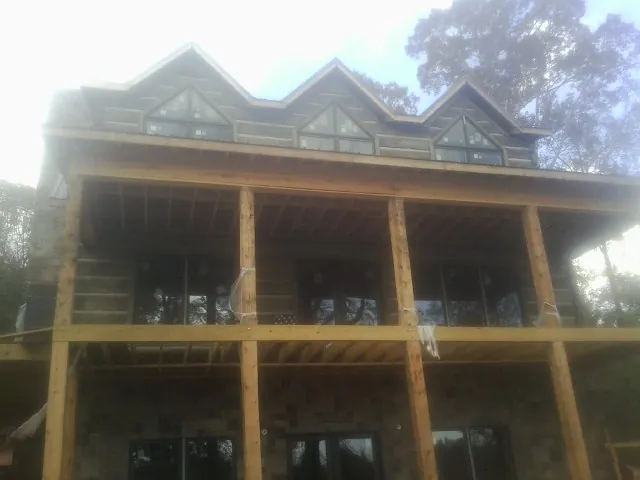Dormers and porch framing on a large log home under construction — Roof Coating work by our crew in Skaneateles Falls