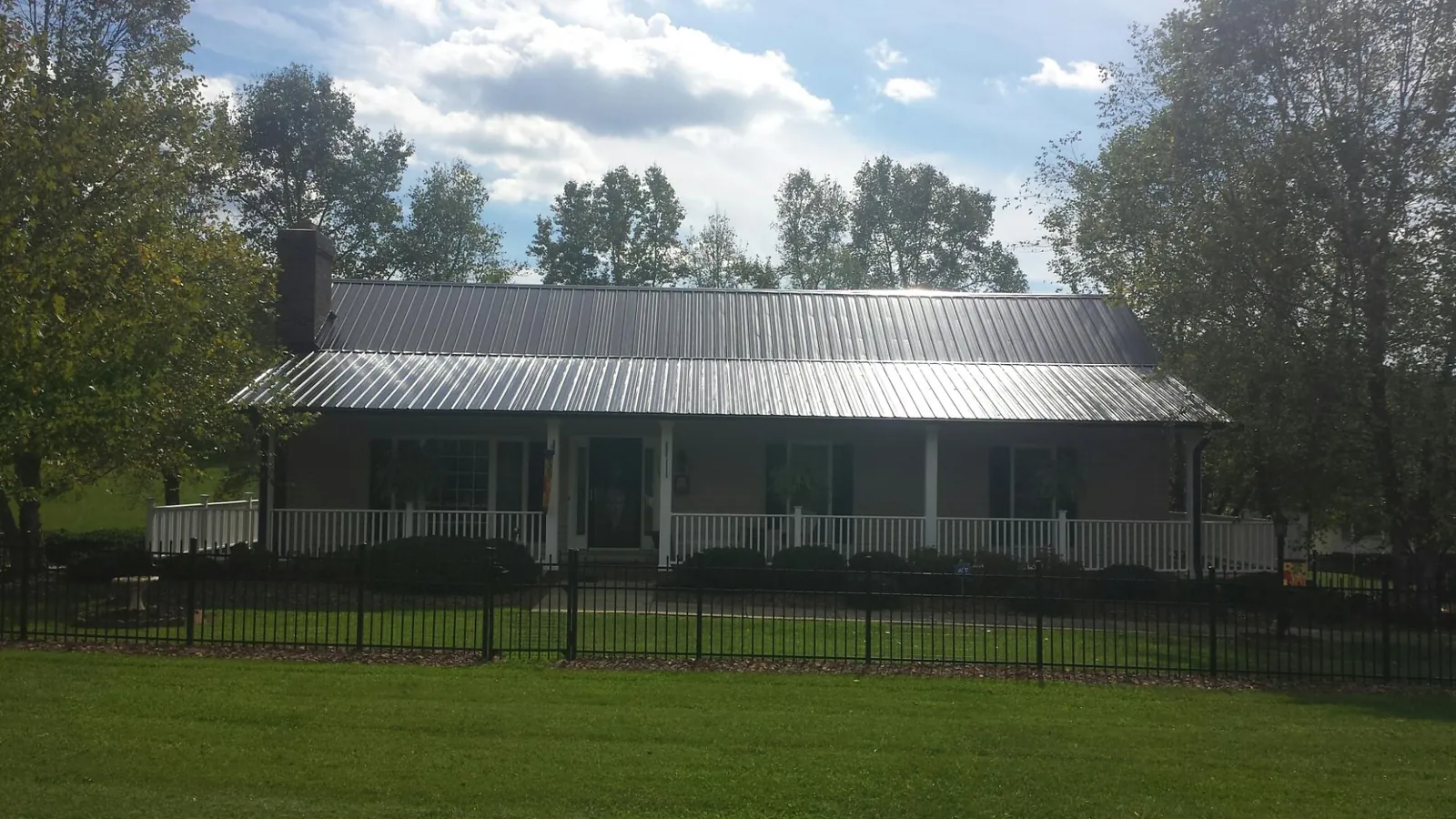 Gray metal roof on a brick ranch with a full width front porch — Gutter Guard Installation work by our crew in Skaneateles Falls