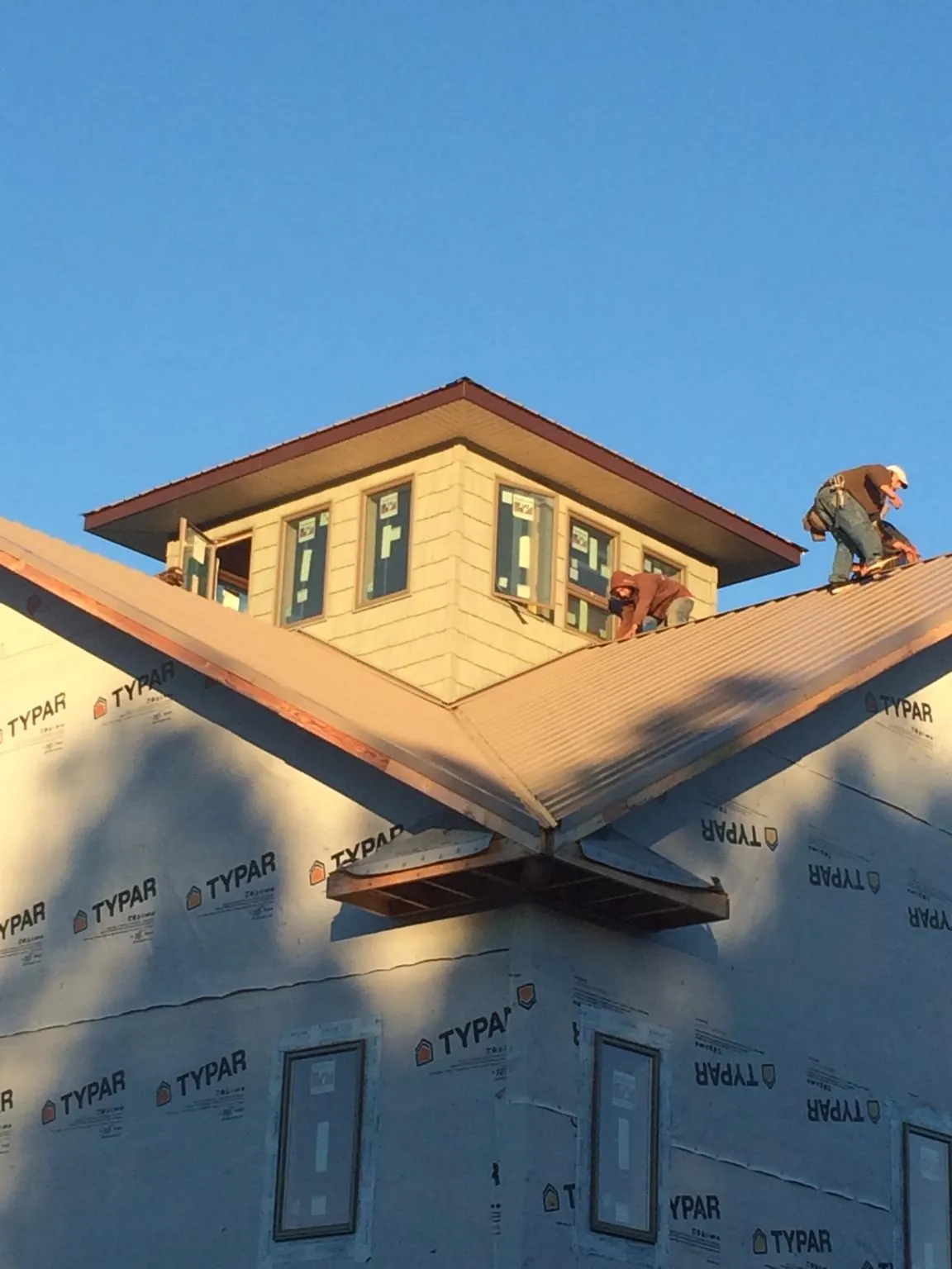 Roofers working around a rooftop cupola on a new metal roof at sunset — Roof Waterproofing in Skaneateles Falls by Roofing Brothers